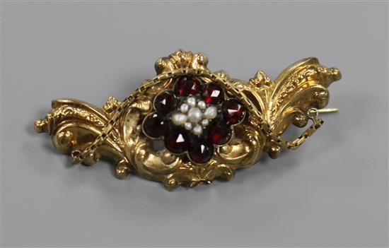 A late Victorian, yellow metal, garnet and pearl scroll brooch, 52mm.